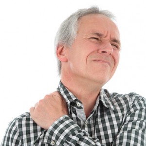 Ein Mann mit einem schmerzhaft verzogenen Gesicht der sich den Schulterbereich hält