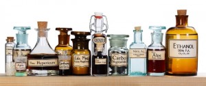 Man sieht verschiedene homöopathische alte Arzneimittelflaschen nebeneinander auf einem Regal aufgestellt,