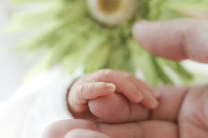 Man sieht eine Babyhand und Ausschnitte einer Erwachsenenhand, die sich berühren