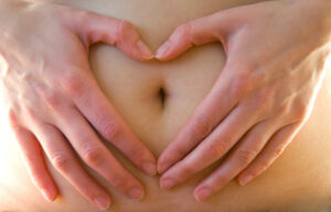 ein nackter Bauch , bei dem um den Nabel mit den Händen ein Herz geformt wird. Entsannende Lymphmassage in hormonellen Umstellungsphasen für Frauen, Dagmar Klein